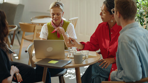Team gathers for brainstorming around a laptop in a coworking cafe