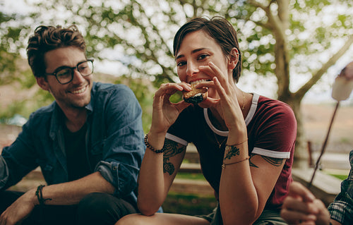 Woman on a holiday eating biscuit sandwich sitting outdoors