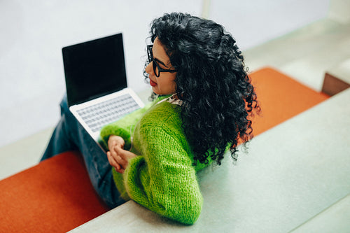 Portrait of a woman with glasses and laptop in a casual indoor workspace