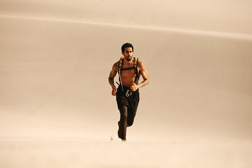 Muscular man running on sand dunes