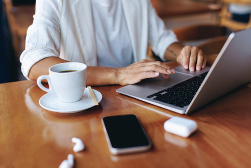 Businesswoman working remotely with laptop and smartphone in a coffee shop