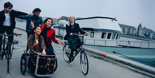 Friends cycling to a party on a festive evening by the waterfront