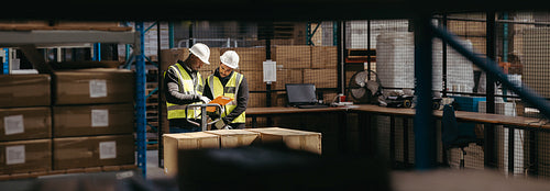 Warehouse employees reading a clipboard in a logistics centre