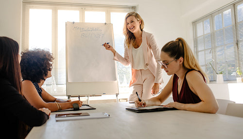 Woman giving presentation on budget to colleagues