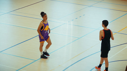 Women playing basketball on indoor court
