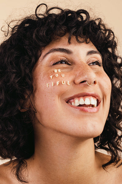 Happy young woman smiling with the word "BEAUTIFUL" written on h