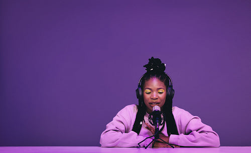 Female podcaster whispering into a microphone in a recording studio
