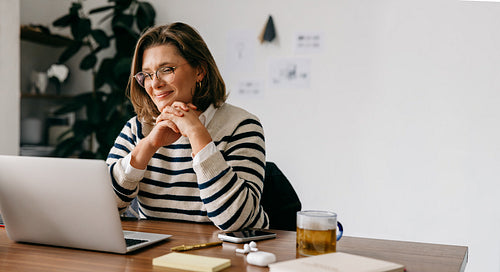 The woman joins a video call on her laptop in a quiet home office