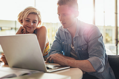 Two young students using laptop in class