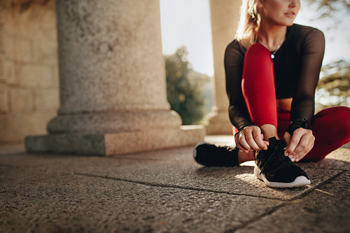 Fitness woman tying her shoe lace sitting on floor