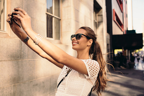 Young tourist recording selfie while walking in the street.
