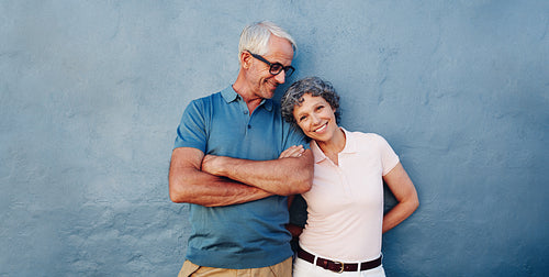Happy senior couple standing together against blue wall