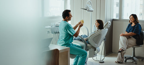 Dentist explains dental care to child during family clinic visit