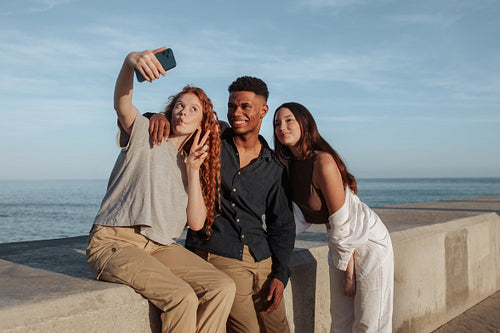 Three friends taking a selfie together next to the sea