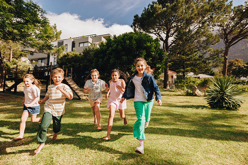 Children running and playing outdoors on a sunny day in a yard
