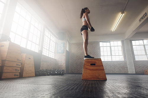 Fit young female standing on a box at gym