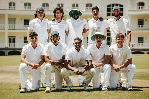 Team of cricket players posing on the field in white uniforms