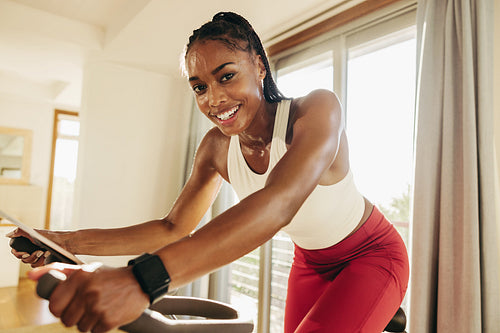 Happy young woman crushing her fitness goals with home cycling equipment