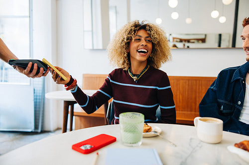 Woman making a payment at a cafe smiling
