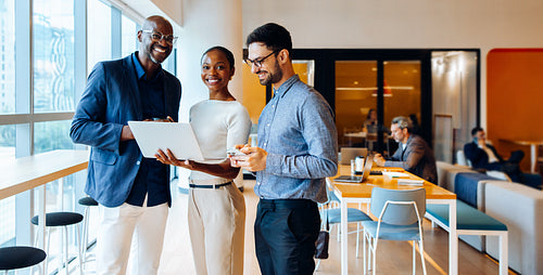 Three colleagues share ideas while discussing a project in a bright office space