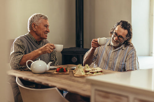 Retired friends enjoying tea and snacks at home