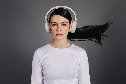 Portrait of a young woman listening to an audio playlist on headphones