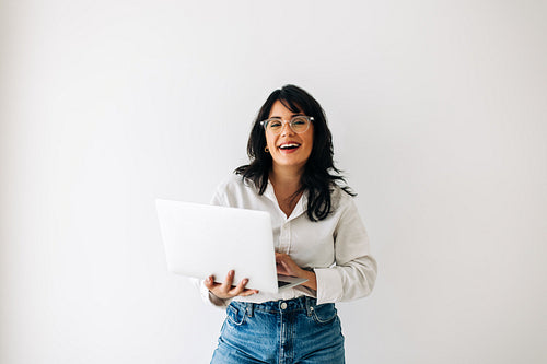 Business woman smiling and using a laptop in an office