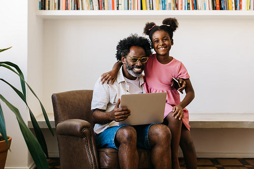 Afro-haired father and daughter using a laptop in happy home