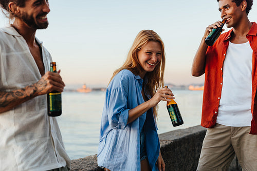 Friends enjoying beers by the waterside at sunset gathering