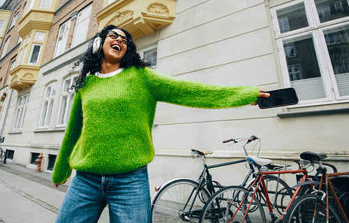 Woman listening to music on a city walk with headphones and smartphone