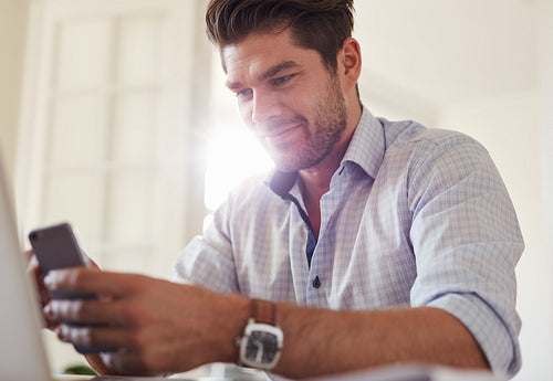 Handsome young man at home using mobile phone