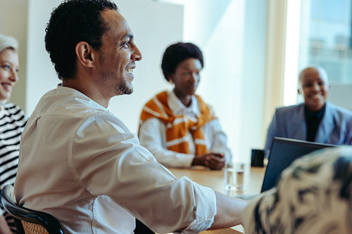 Male employee engaging in person with colleagues during a contemporary teamwork meeting