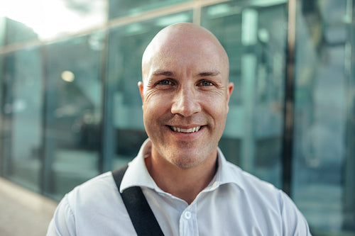 Happy businessman smiling at the camera outside his workplace