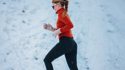Side view running captures the woman in winter snow on a hillside route