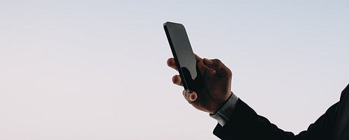 Young man's hand holding a smartphone as he reads messages on a mobile app