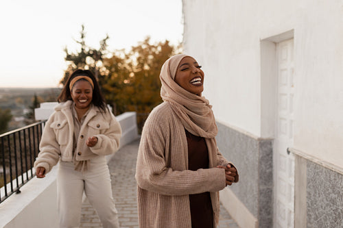 Two happy young women laughing together outdoors
