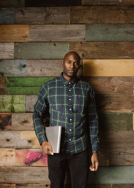 Portrait of a handsome young with laptop against a wooden wall