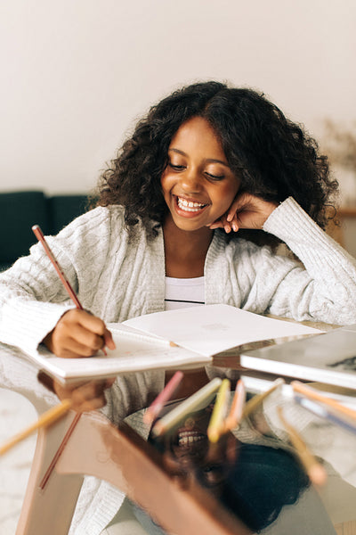 Girl writing in her book at home