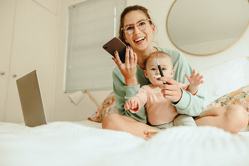 Happy mom taking a phone call while sitting with her baby