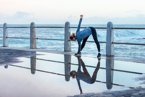 Woman doing stretching workout on wet road