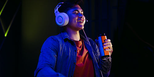 Refreshed gamer holding a can of energy drink at night