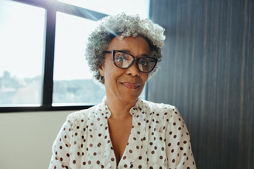 Woman with glasses sits in an office with natural light