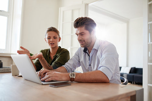 Young man and woman at home using laptop