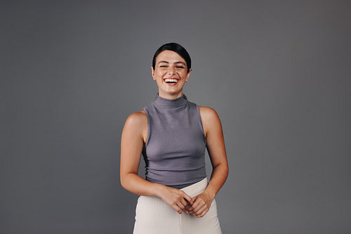 Portrait of a happy young woman laughing and looking at the camera in a studio