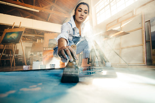 Skilful young artist painting on a canvas with a paintbrush