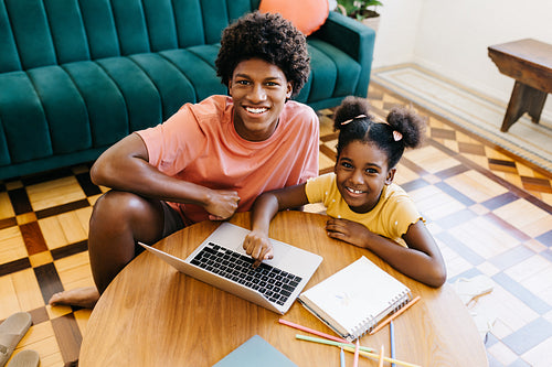 Siblings studying together at home with online tutorials