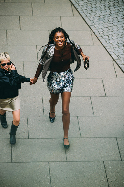 City friendship: laughing friends walking hand in hand