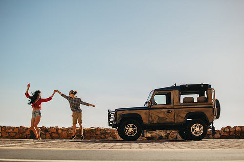 Couple dancing in front of their car