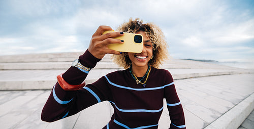 Smiling woman taking photograph outdoors with phone