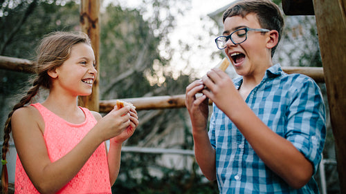 Kids eating picnic food standing outdoors